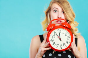 Woman holding clock using time management tools to be more productive